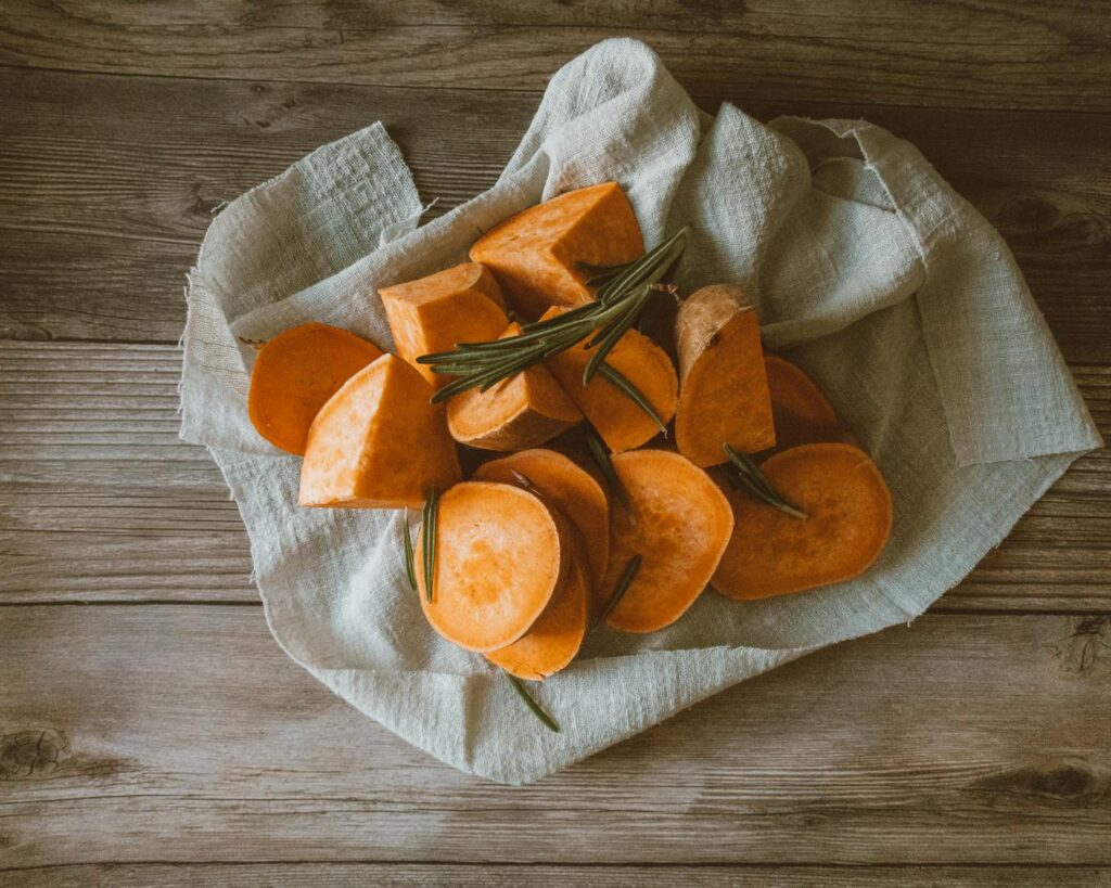 A rustic setting with sliced sweet potatoes on a wooden surface, perfect for fall recipes.