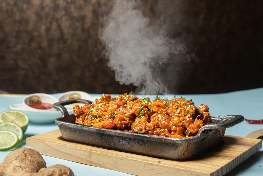 Delicious spicy chicken served hot in a rustic pan with fresh herbs.