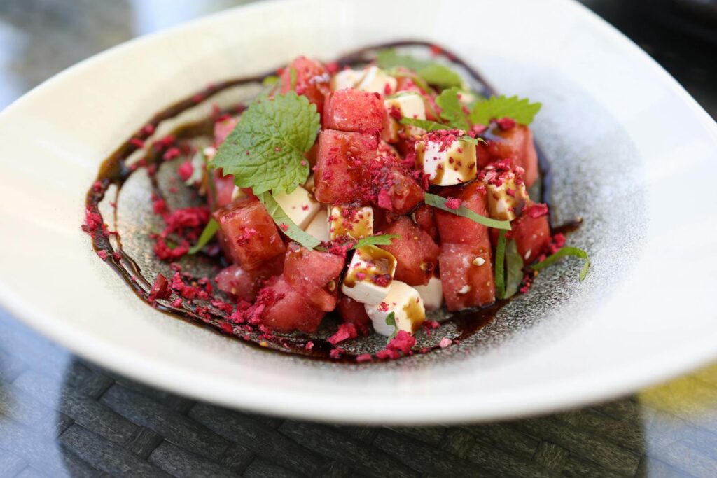 Close-up image of a vibrant watermelon and feta salad garnished with mint leaves.