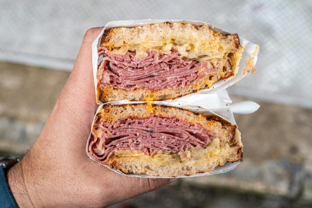 Tasty pastrami sandwich held close-up for delicious food presentation.