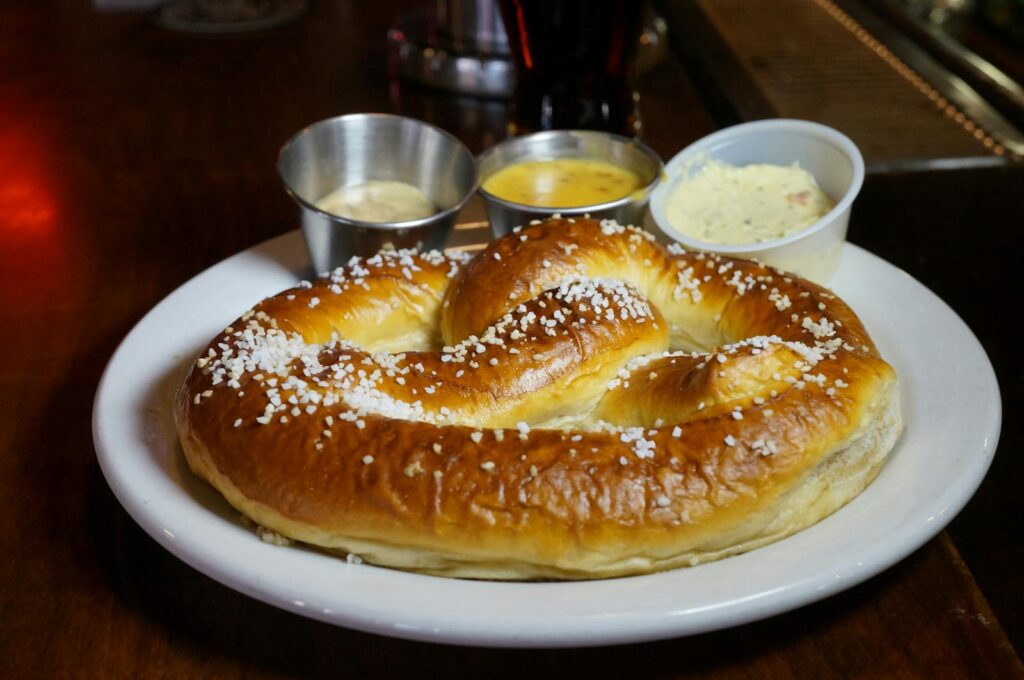 Delicious warm pretzel served with mustard, cheese, and butter dips in a cozy Austin setting.