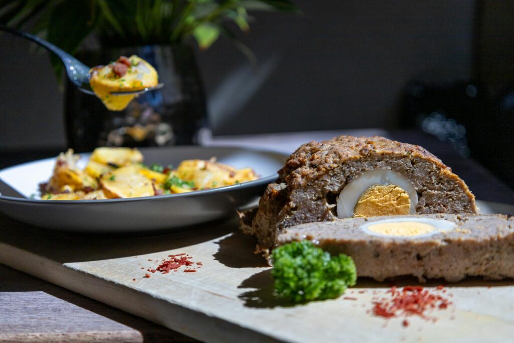 Tasty meatloaf with egg centerpiece served with potatoes. Perfect for a hearty meal.