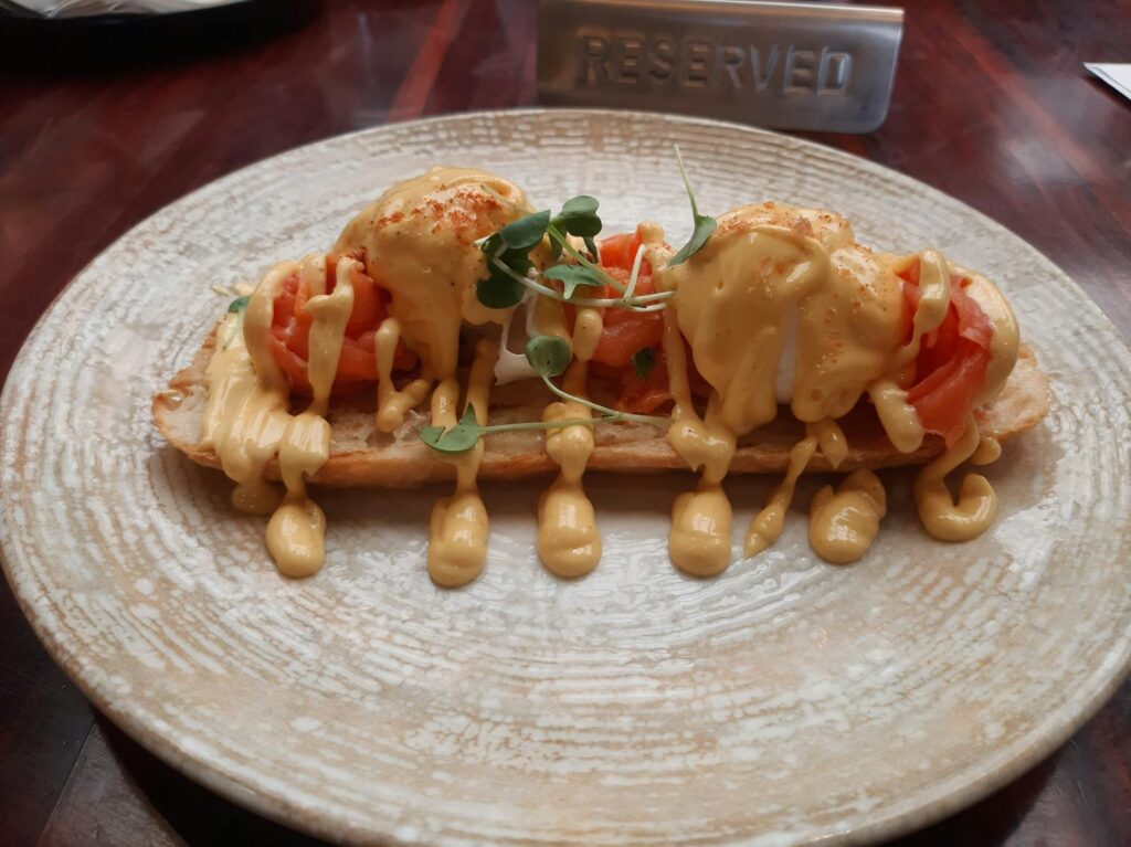 Delicious egg benedict with smoked salmon and hollandaise sauce served on crusty bread.