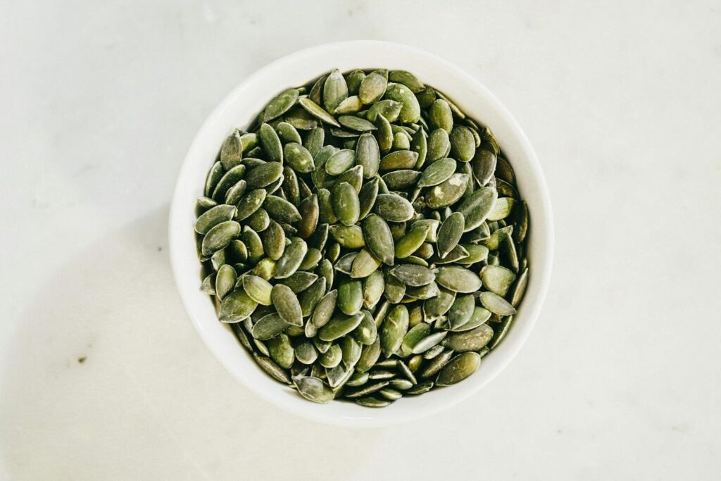 A bowl filled with fresh green pumpkin seeds, ideal for healthy eating.