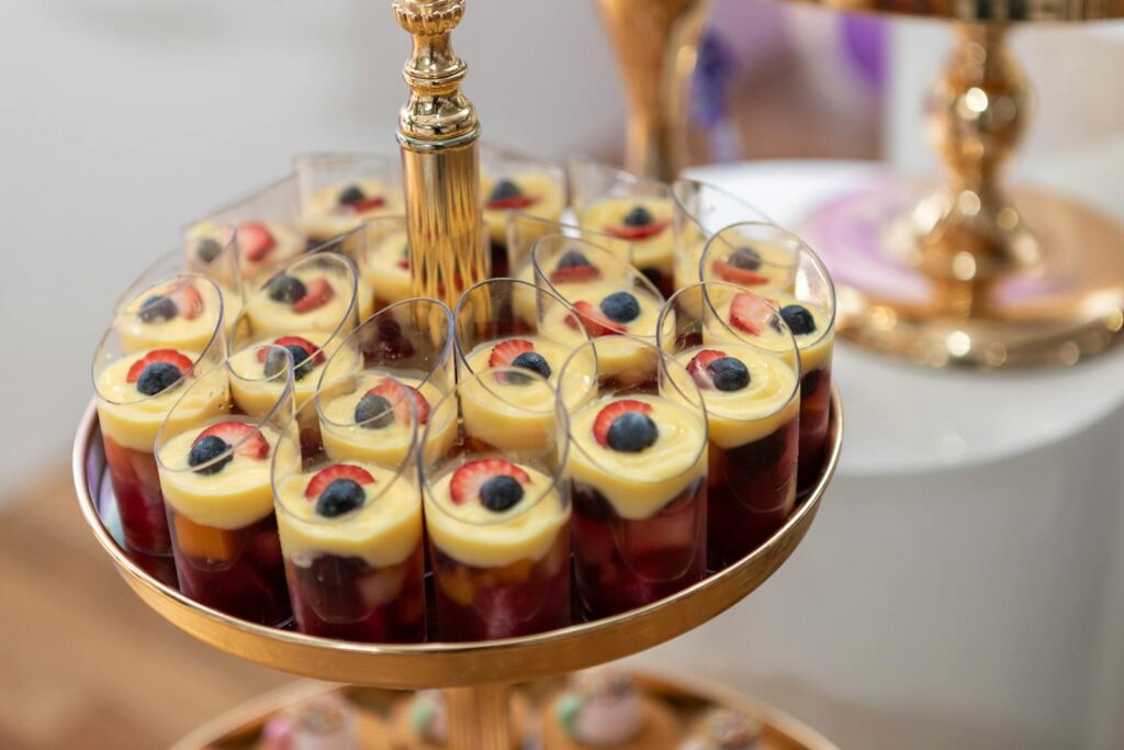 A sophisticated arrangement of fruit-topped desserts served in transparent cups, ideal for events.