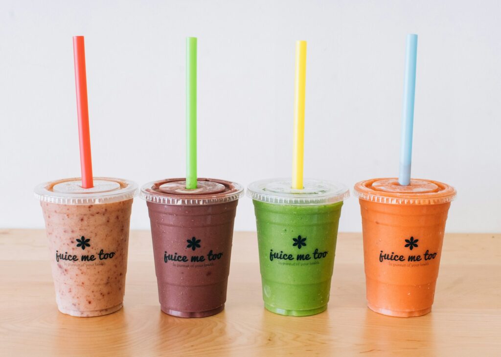 three cups of smoothie with straws on a table