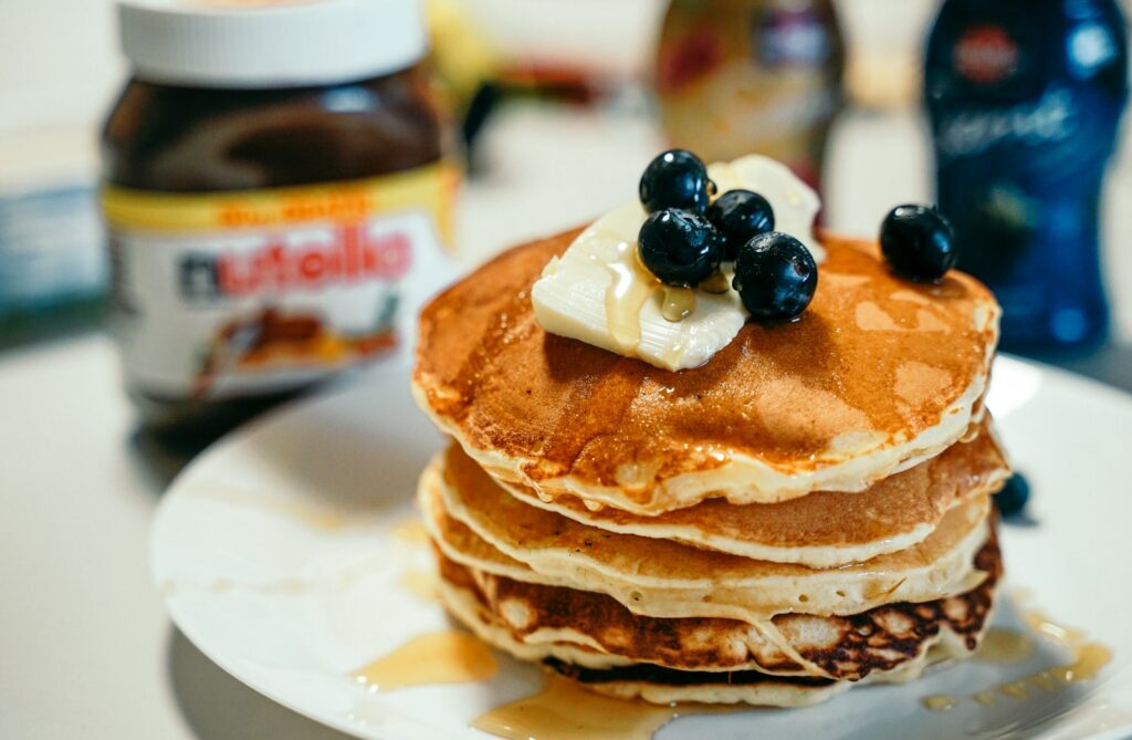 a stack of pancakes topped with blueberries and butter