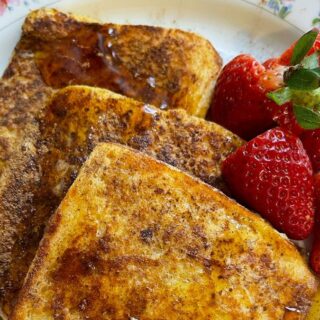Tasty french toast served with fresh strawberries on a floral plate.