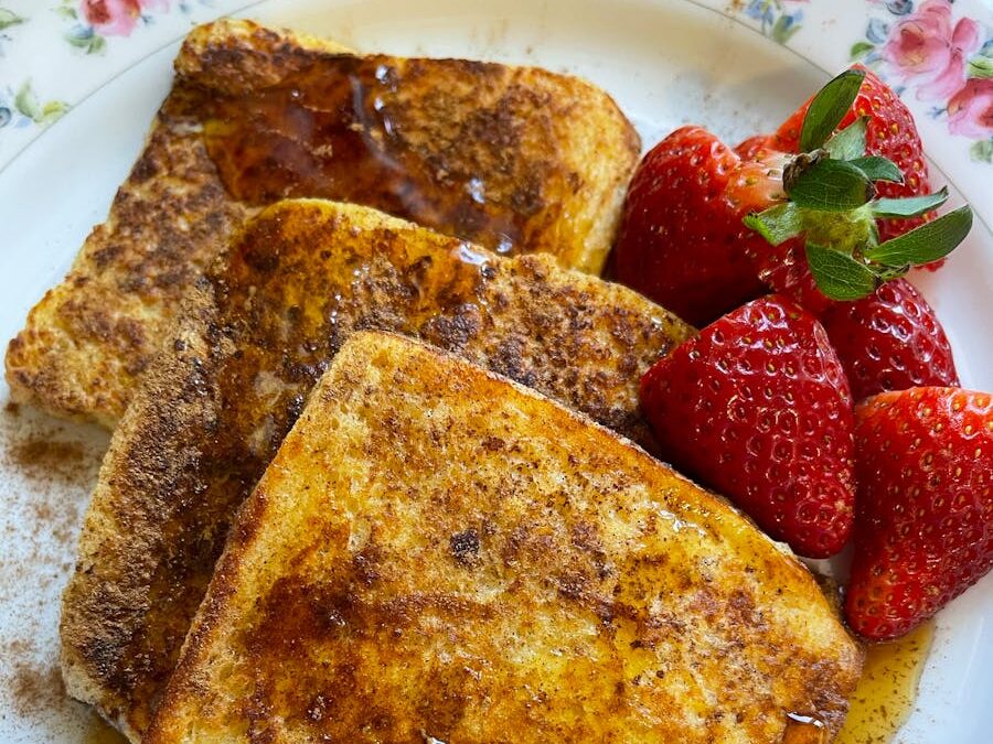 Tasty french toast served with fresh strawberries on a floral plate.