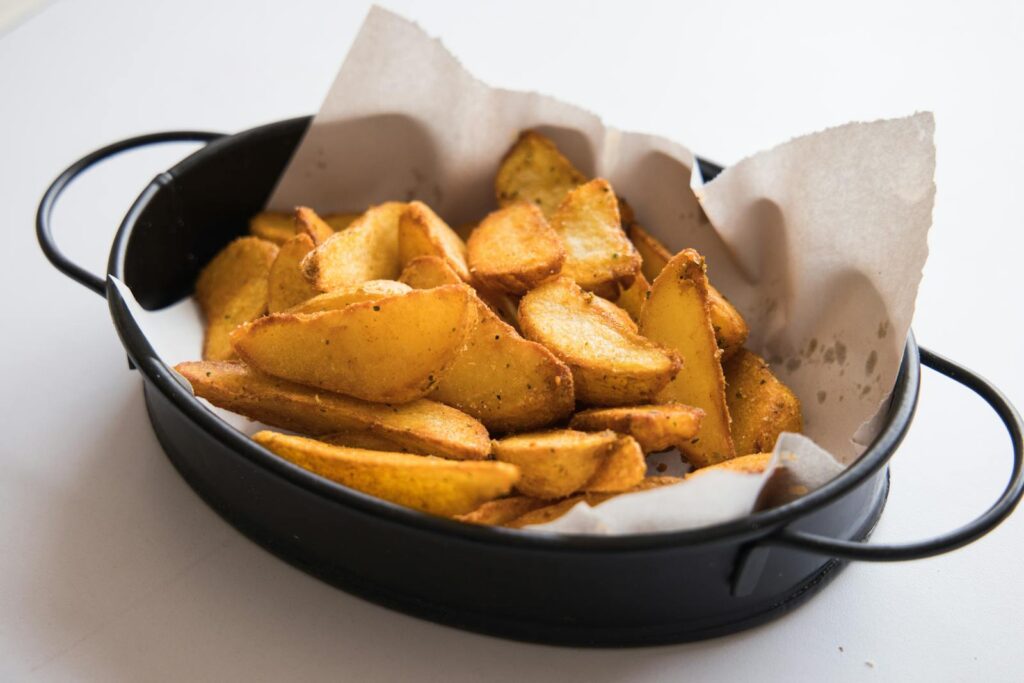 Freshly baked potato wedges served in a stylish black bowl, perfect for a snack or appetizer.