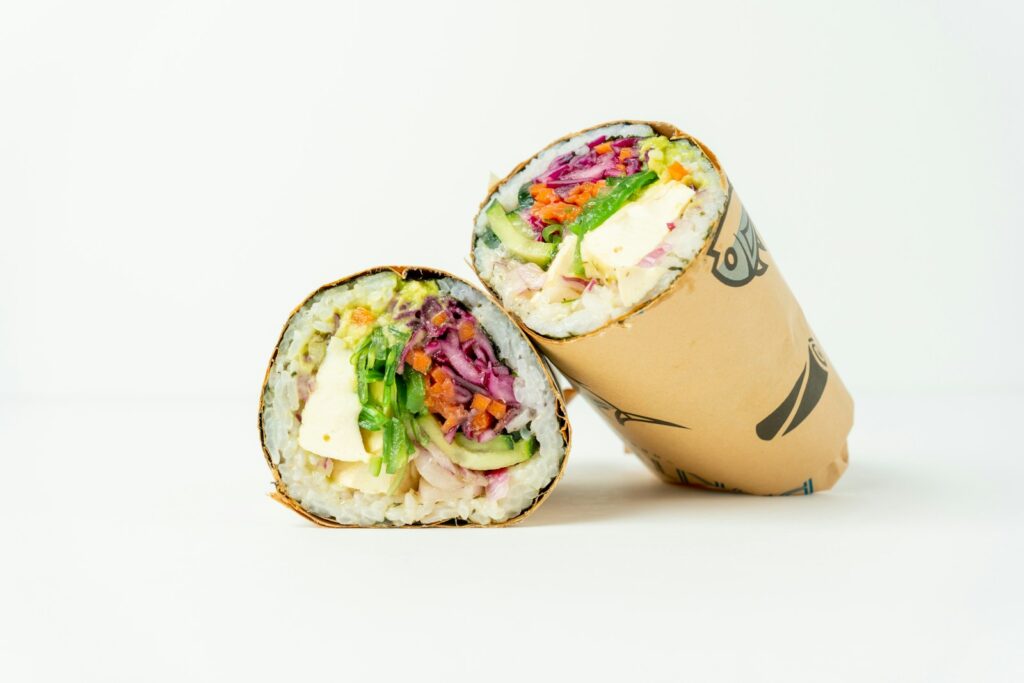 Two sushi rolls sitting next to each other on a white surface
