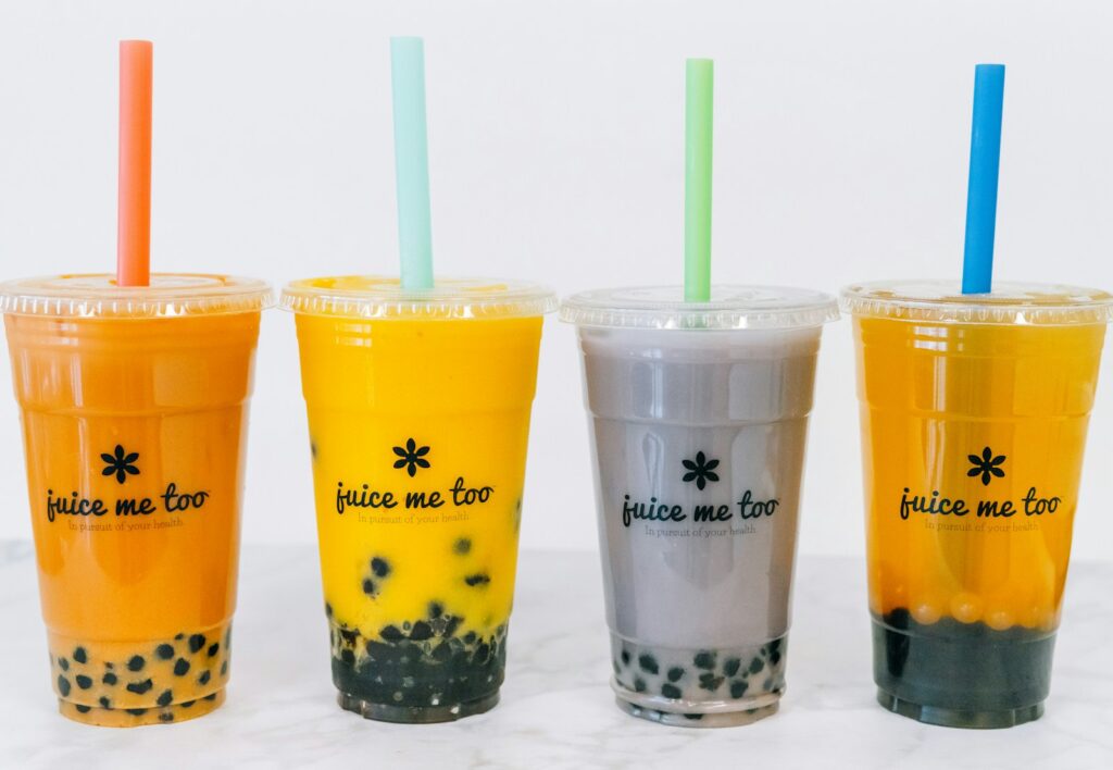 Four colorful boba teas with straws.