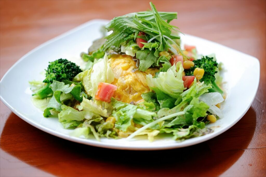 A white plate topped with a salad on top of a wooden table