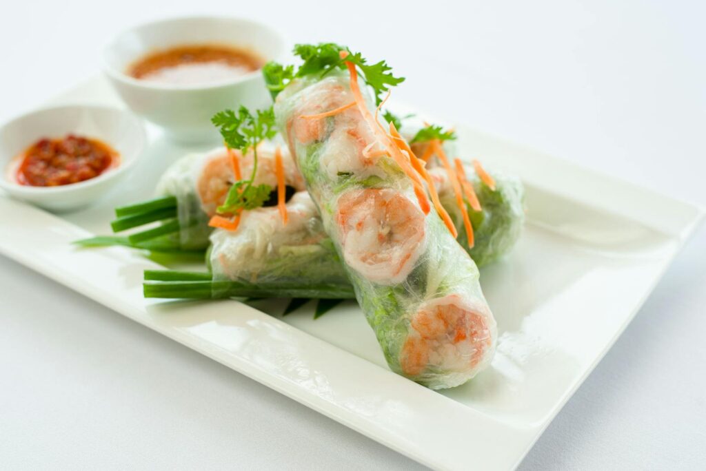 Fresh Vietnamese spring rolls on a plate with dipping sauces, perfect for food photography and culinary inspiration.