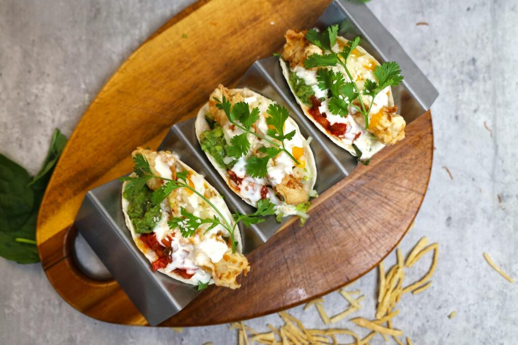 Three appetizing tacos filled with fresh ingredients served on a stylish wooden board.