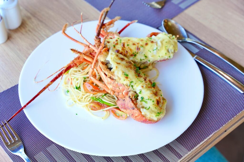 Savor a mouthwatering baked lobster served with spaghetti in a gourmet setting.