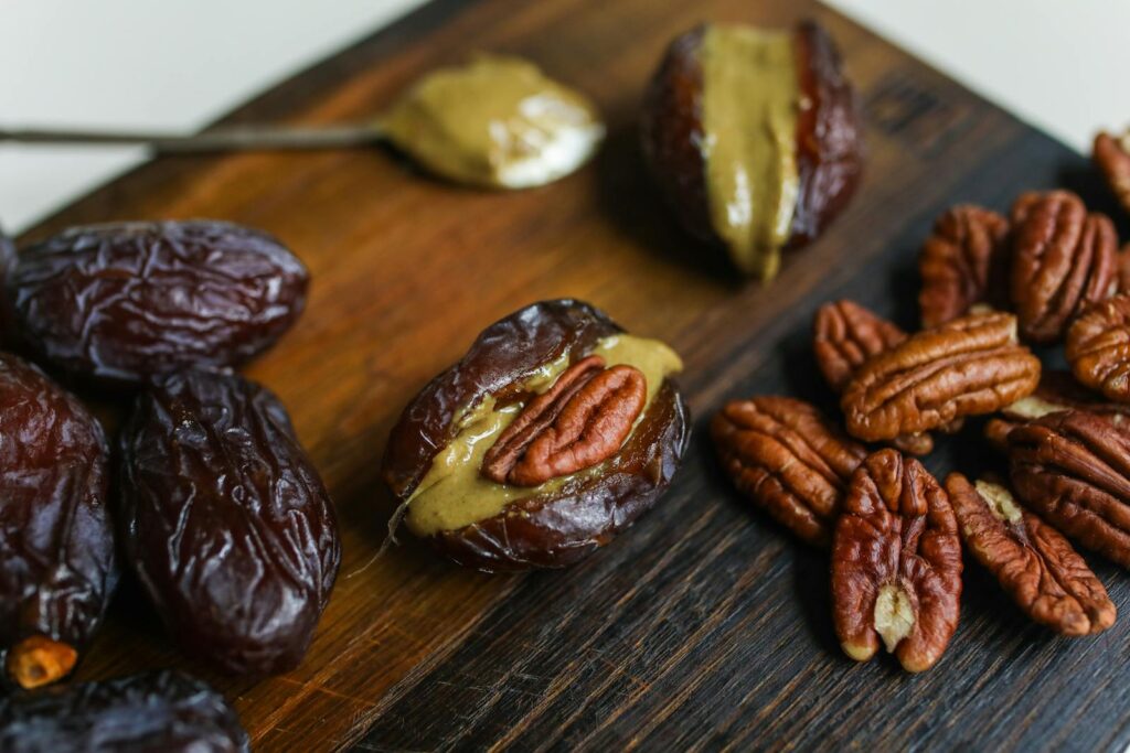 Close-up view of dates filled with pecans and nut butter on a wooden surface, ideal for healthy cooking concepts.