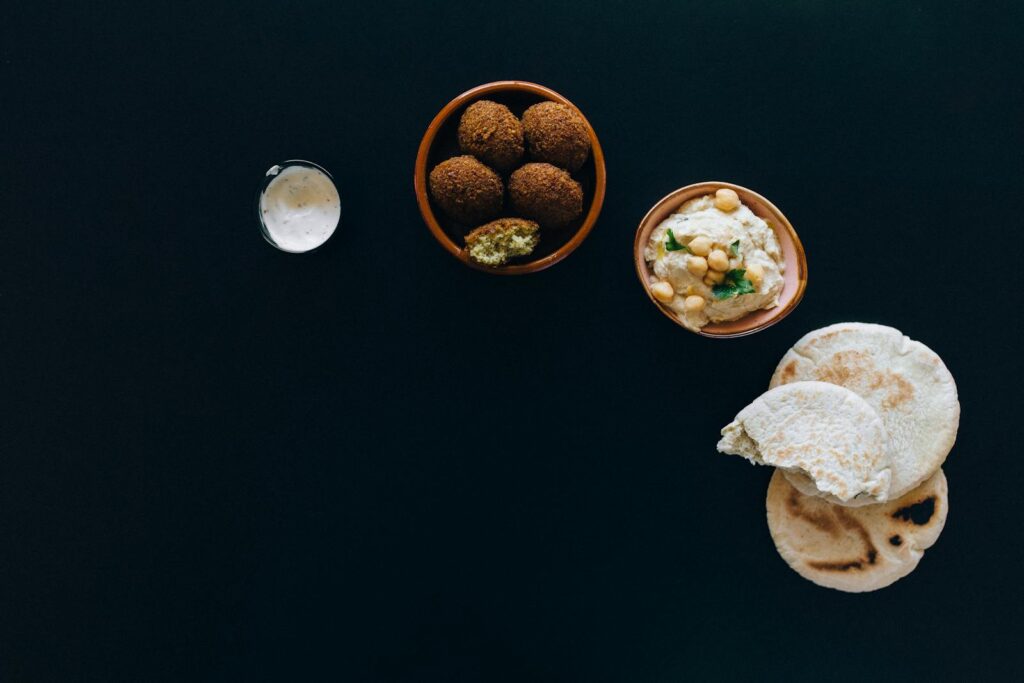 A delicious spread of falafel, hummus, and pita bread on dark background.