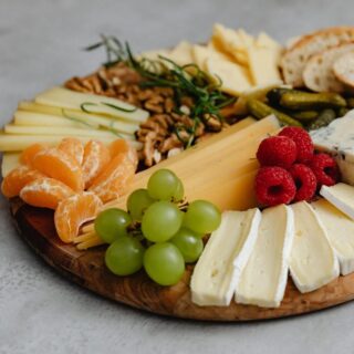 A visually appealing cheese platter with an assortment of fruits, nuts, and crackers.