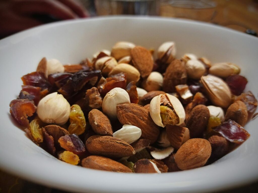 Close-up of mixed nuts and dried fruits in a white bowl, showcasing healthy snacks.