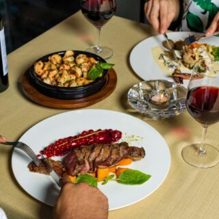 A sophisticated meal setting with gourmet dishes and red wine for a fine dining experience.