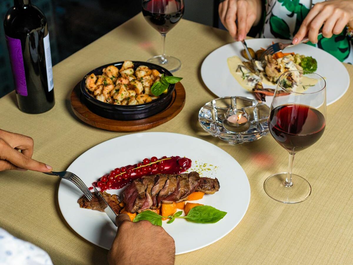 A sophisticated meal setting with gourmet dishes and red wine for a fine dining experience.