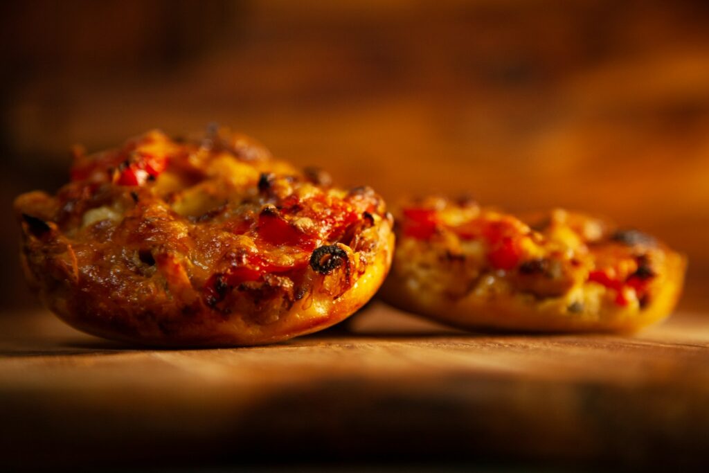 a couple of small pizzas sitting on top of a wooden table
