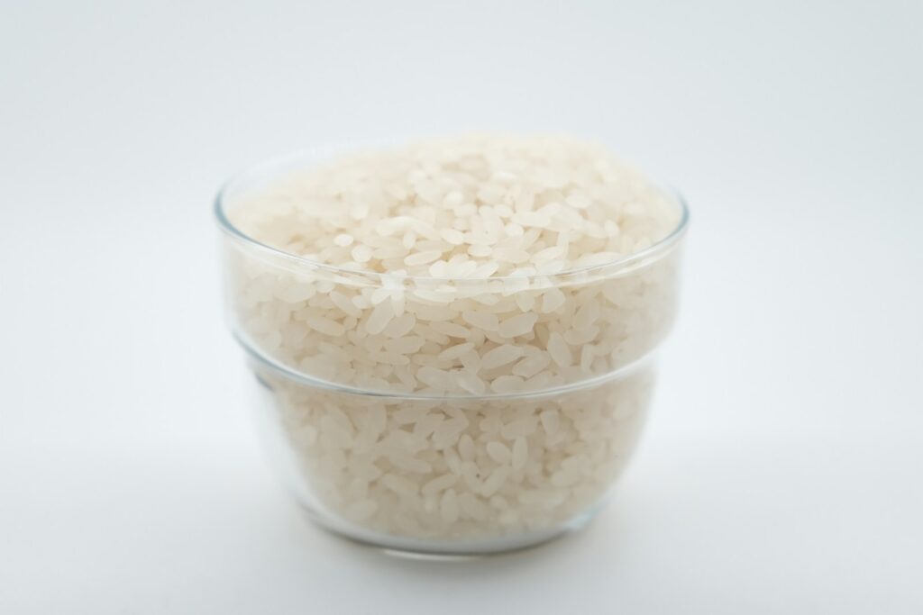 a glass bowl filled with rice on top of a white table